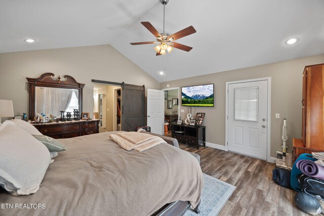 bedroom featuring a barn door, ceiling fan, wood-type flooring, and vaulted ceiling