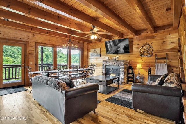 living room with a fireplace, ceiling fan with notable chandelier, a healthy amount of sunlight, and light hardwood / wood-style flooring