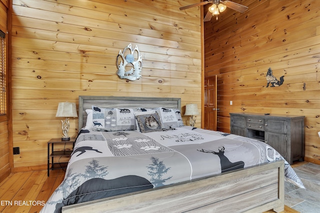 bedroom with light hardwood / wood-style flooring, ceiling fan, and wood walls