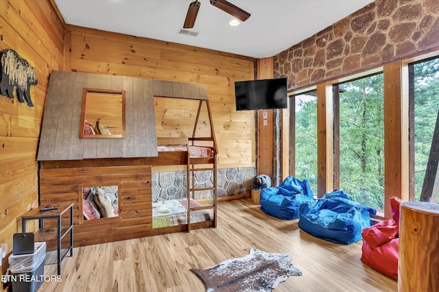 interior space featuring ceiling fan, wooden walls, and light hardwood / wood-style floors