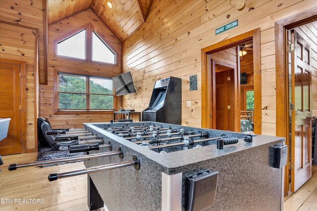 kitchen featuring light wood-type flooring, high vaulted ceiling, wooden walls, stainless steel gas cooktop, and wooden ceiling