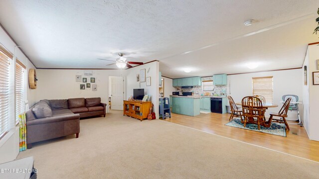 carpeted living room with lofted ceiling, a textured ceiling, ceiling fan, and ornamental molding