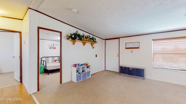 recreation room with crown molding, wood-type flooring, and lofted ceiling