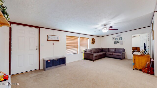 living room featuring ceiling fan, light colored carpet, ornamental molding, and a textured ceiling