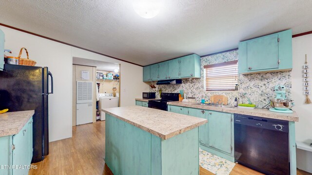 kitchen featuring black appliances, a kitchen island, washer / dryer, and light hardwood / wood-style floors