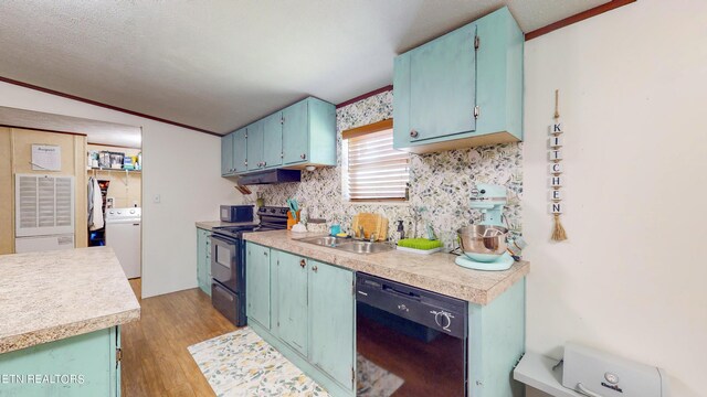 kitchen featuring sink, black appliances, light hardwood / wood-style flooring, washer / clothes dryer, and lofted ceiling