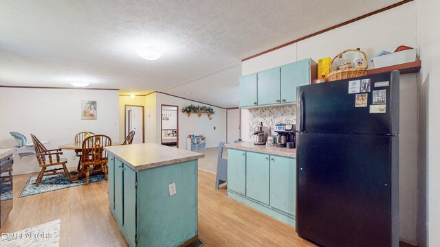 kitchen featuring a center island, black refrigerator, light hardwood / wood-style floors, and a textured ceiling