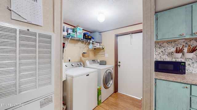 clothes washing area with washing machine and dryer, light wood-type flooring, and ornamental molding