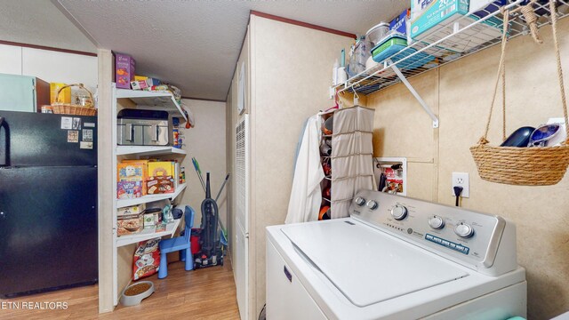 laundry area with a textured ceiling, washer / clothes dryer, and light hardwood / wood-style flooring