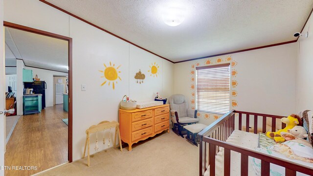 carpeted bedroom featuring black fridge, a nursery area, and a textured ceiling