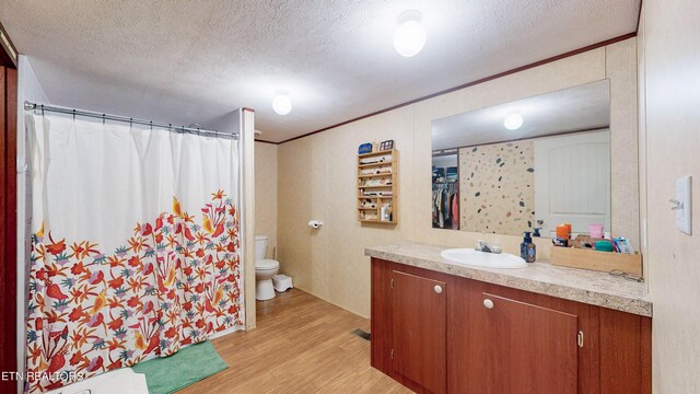 bathroom with hardwood / wood-style floors, vanity, a textured ceiling, and toilet