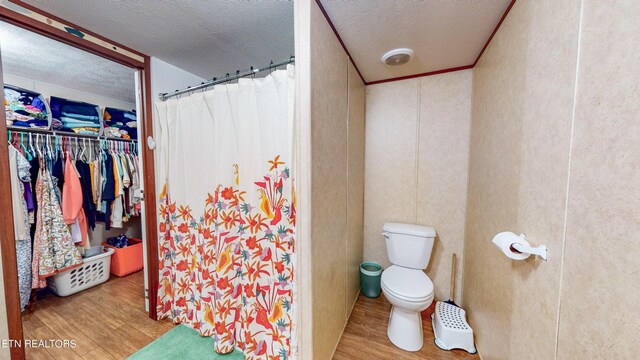 bathroom featuring wood-type flooring, a textured ceiling, and toilet