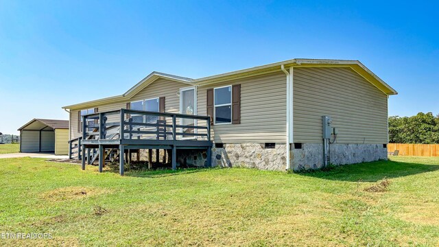 rear view of property featuring a yard, a garage, and a deck