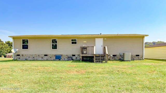 rear view of house with central AC unit and a lawn