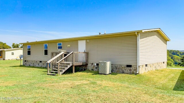 back of house featuring central AC unit and a lawn