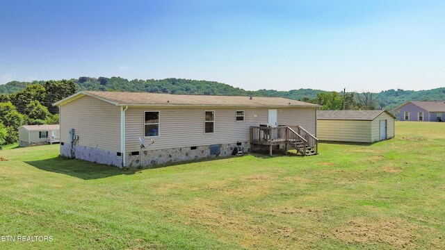 rear view of house featuring a storage unit and a yard