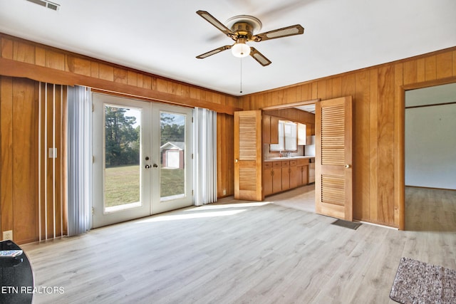 unfurnished bedroom with multiple windows, ceiling fan, light hardwood / wood-style floors, and french doors