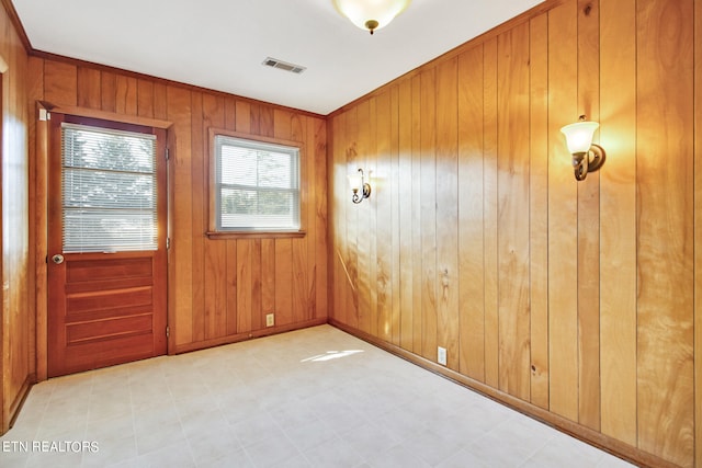 unfurnished room featuring ornamental molding and wood walls