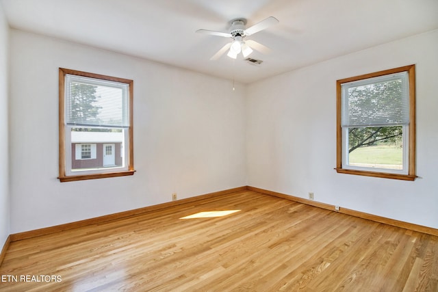 spare room featuring a healthy amount of sunlight, ceiling fan, and light hardwood / wood-style floors