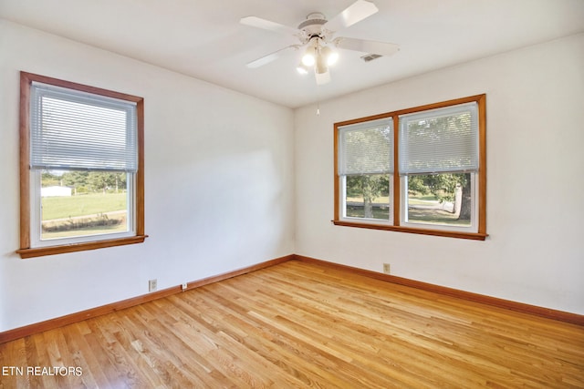 empty room with plenty of natural light, ceiling fan, and light hardwood / wood-style flooring