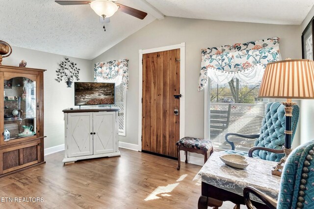 interior space with lofted ceiling with beams, a textured ceiling, hardwood / wood-style flooring, and ceiling fan