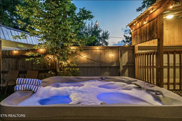 pool at dusk with a hot tub