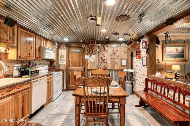 kitchen featuring white appliances, stone counters, light tile patterned flooring, and sink