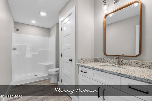 bathroom featuring toilet, walk in shower, wood-type flooring, and vanity