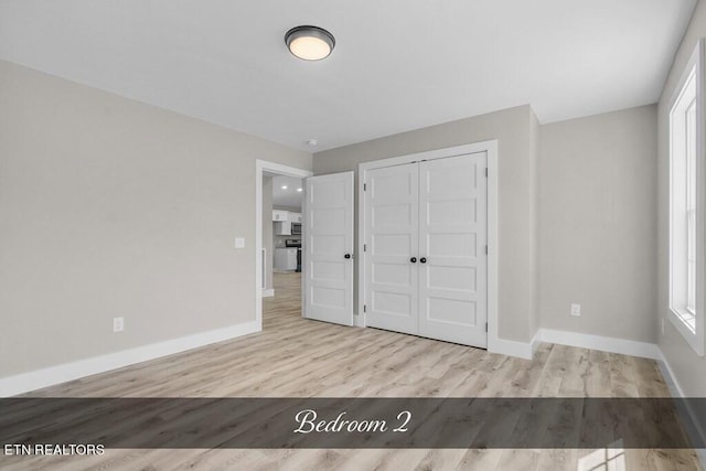 unfurnished bedroom with a closet and light wood-type flooring