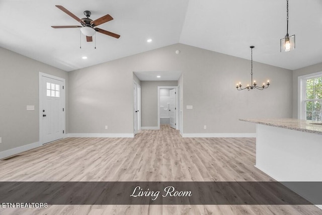 unfurnished living room featuring vaulted ceiling, ceiling fan with notable chandelier, and light hardwood / wood-style floors