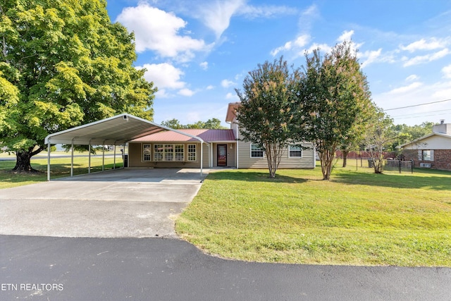 view of front of home with driveway, metal roof, fence, a carport, and a front yard