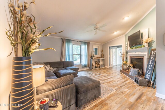 living room featuring ceiling fan, vaulted ceiling, ornamental molding, and light hardwood / wood-style floors