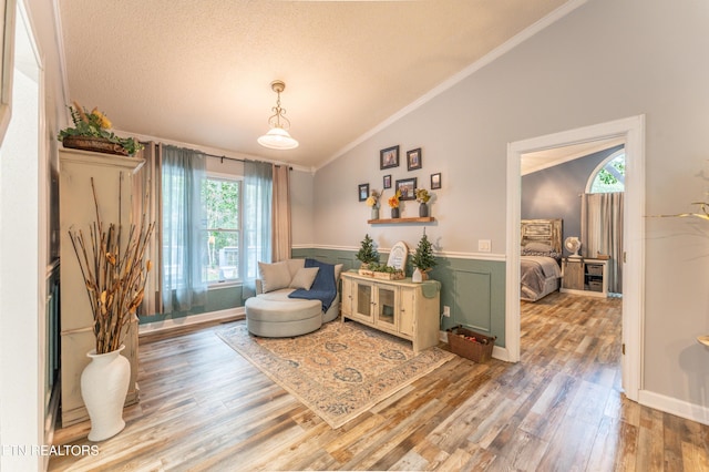 sitting room featuring hardwood / wood-style flooring, a textured ceiling, crown molding, and vaulted ceiling