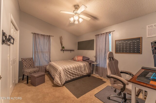 carpeted bedroom with a textured ceiling, ceiling fan, a closet, and vaulted ceiling