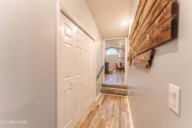 corridor featuring light wood-type flooring and a textured ceiling