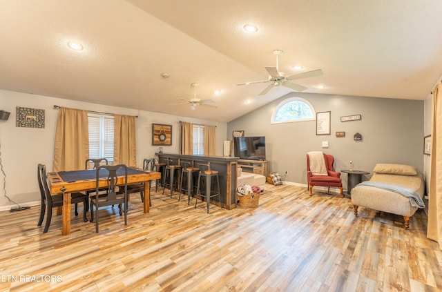 dining room featuring lofted ceiling, a textured ceiling, and light hardwood / wood-style floors