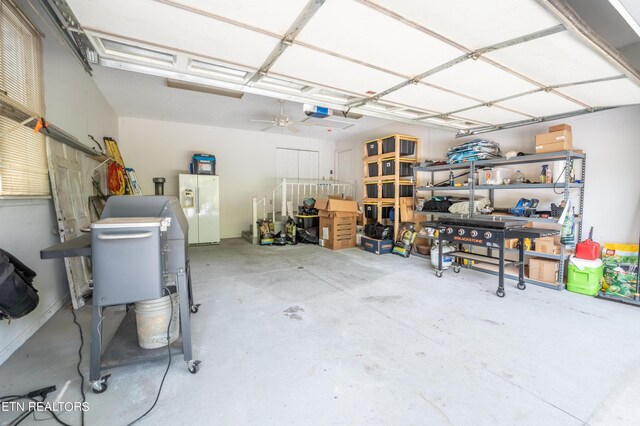 garage featuring white refrigerator with ice dispenser and a garage door opener