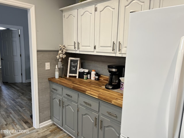 bar featuring wood-type flooring, white cabinetry, butcher block counters, and white fridge