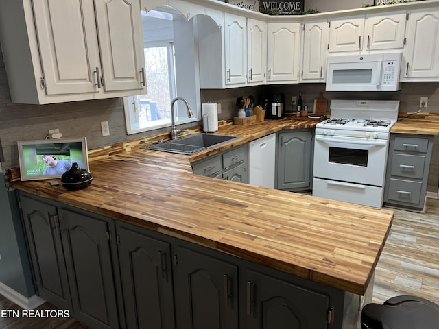 kitchen featuring sink, white appliances, white cabinets, and wood counters