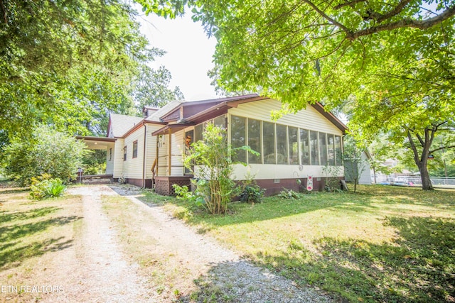 view of front facade with a sunroom and a front lawn