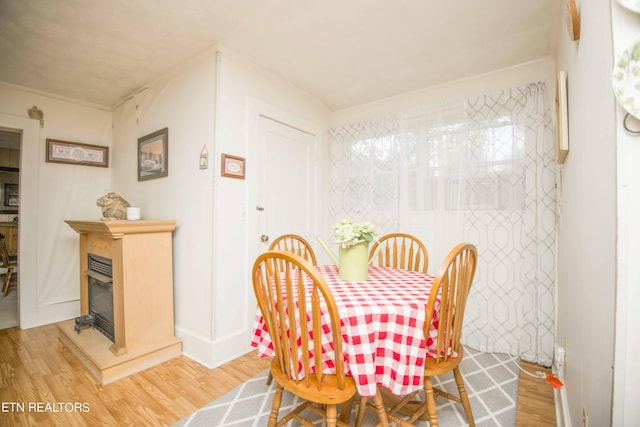 dining room with light wood-type flooring and a glass covered fireplace