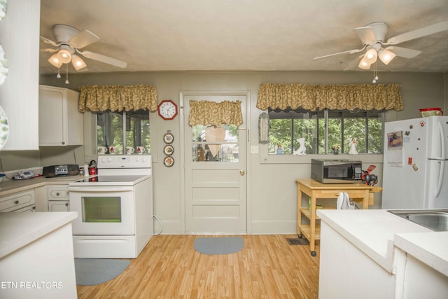 kitchen with white appliances, light countertops, plenty of natural light, and light wood-style flooring