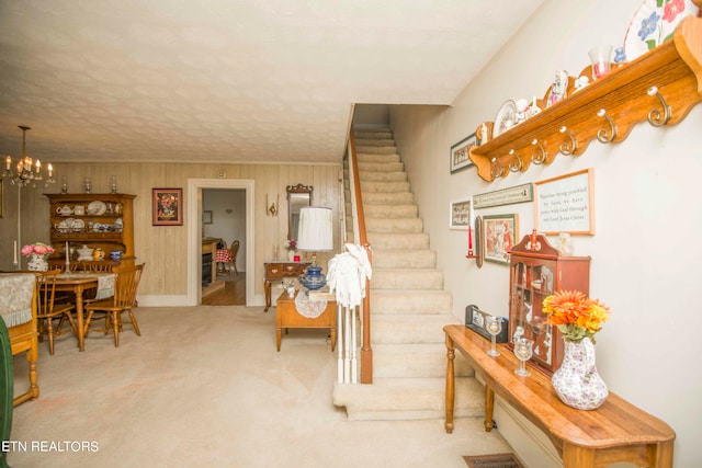 stairway featuring wood walls, a chandelier, a textured ceiling, and carpet floors