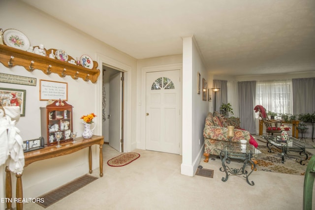 foyer entrance featuring carpet and baseboards