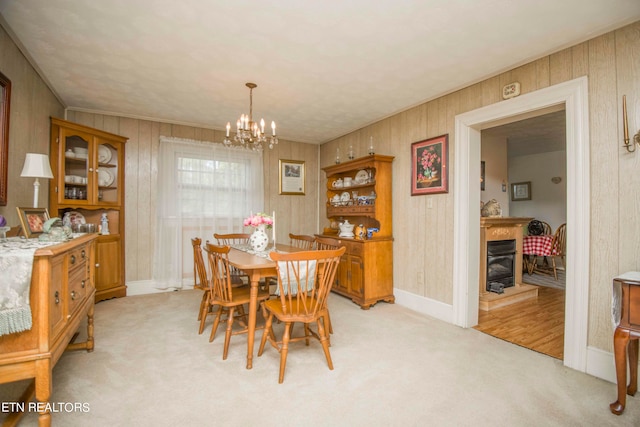 dining area with light carpet, a chandelier, and wood walls