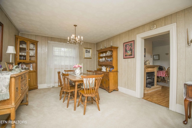 dining room featuring a notable chandelier, baseboards, a glass covered fireplace, and light colored carpet