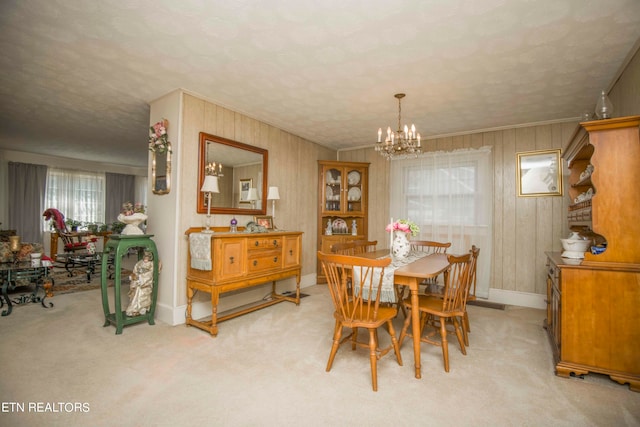 dining area featuring a wealth of natural light, wood walls, an inviting chandelier, and light carpet