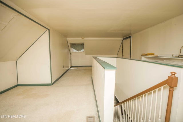 hall with visible vents, an upstairs landing, and light colored carpet