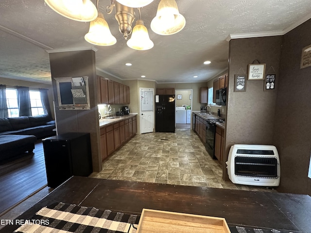 kitchen with heating unit, a sink, crown molding, black appliances, and a notable chandelier