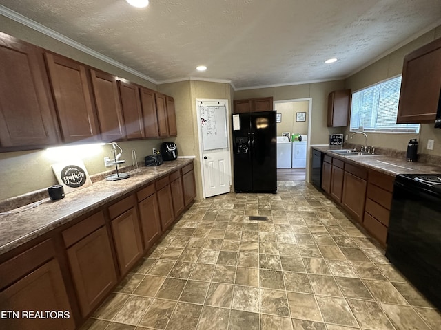 kitchen featuring washer and clothes dryer, stove, a textured ceiling, black fridge, and a sink